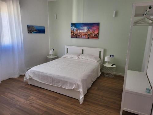 una camera da letto con un letto bianco e un quadro sul muro di Le Case di Sole Appartamento Mondello a Mondello