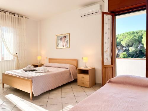 a bedroom with two beds and a large window at Agriturismo La Rondine in Bolgheri