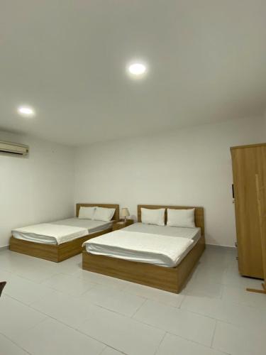 two beds in a room with white walls at Maria Hotel in Ba Tri