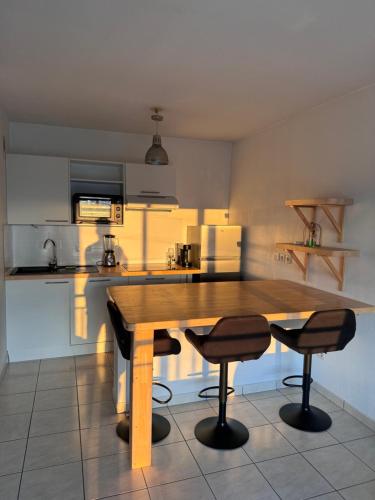 une cuisine avec une table en bois et deux chaises dans l'établissement Appartement 2 chambres Terrasson, à Terrasson