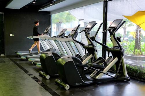 a woman walking past a row of cardio machines in a gym at Sens Club in Thốt Nốt