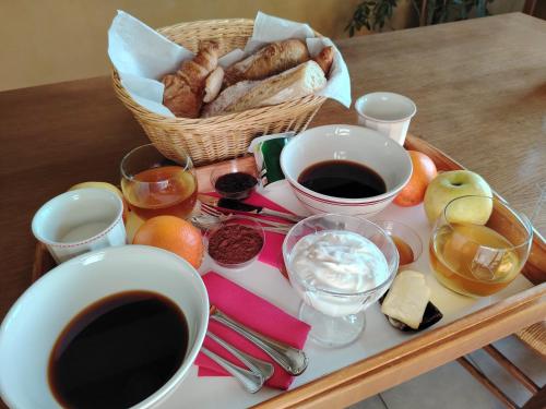 a tray with a basket of bread and a cup of coffee at Gîte Le Vieux Chêne in Lhuis