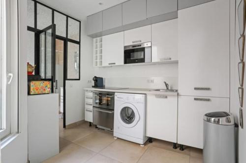 une cuisine blanche avec une machine à laver et un micro-ondes dans l'établissement DesignAppart - Île Saint-Louis, Notre-Dame, Marais, à Paris