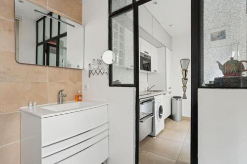 une salle de bain blanche avec un lavabo et un miroir dans l'établissement DesignAppart - Île Saint-Louis, Notre-Dame, Marais, à Paris