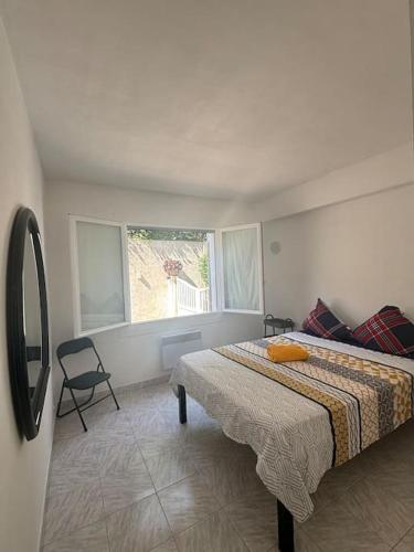une chambre avec un lit, une chaise et une fenêtre dans l'établissement Maison bord de mer Eze, à Èze
