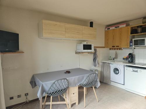 une petite cuisine avec une table et un lave-linge. dans l'établissement Le Diamant - Appt vue montagne, à Embrun
