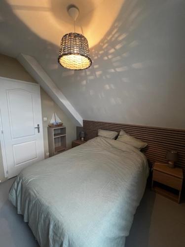 une chambre avec un lit blanc et un lustre dans l'établissement Appartement à la Naturelle, à Wimereux