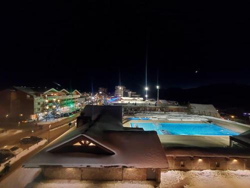 - une piscine de nuit avec une ville en arrière-plan dans l'établissement 60m2 cœur station Esprit Montagne et skis aux pieds, à Huez