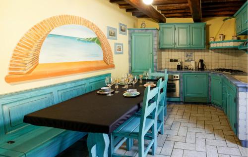 une cuisine avec des placards verts et une table avec des verres à vin dans l'établissement Casa Vacanza Marina, à Corsanico-Bargecchia