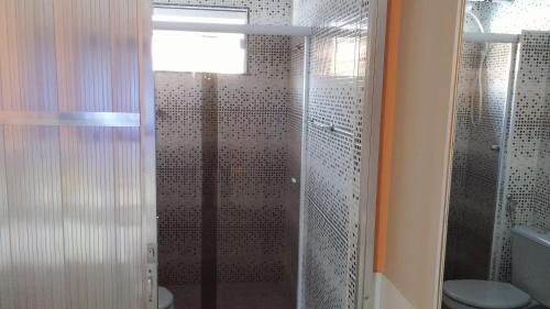 uma casa de banho com uma cabina de duche em vidro e um WC. em Forte Do Pouso Hospedagens em Saquarema