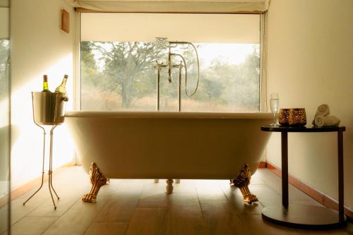 a large bath tub in a bathroom with a window at Tree of Life Ramvilas, Bandhavgarh in Tāla