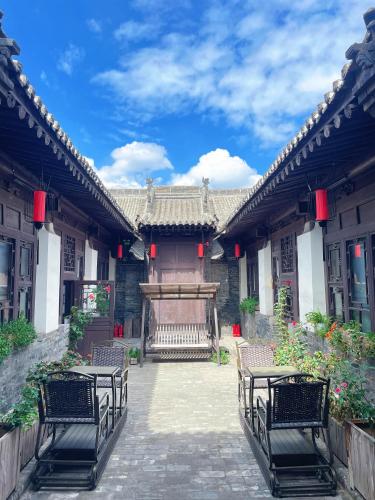 a courtyard of a building with tables and chairs at Elsewhere Hotel Inn Ancient City Center Branch in Pingyao