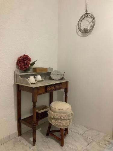 a table with a stool and a vase of flowers on it at Lou jasset in Cabrières-dʼAigues
