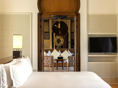 a bedroom with a bed and a dining room at Banyan Tree Tamouda Bay in Fnidek