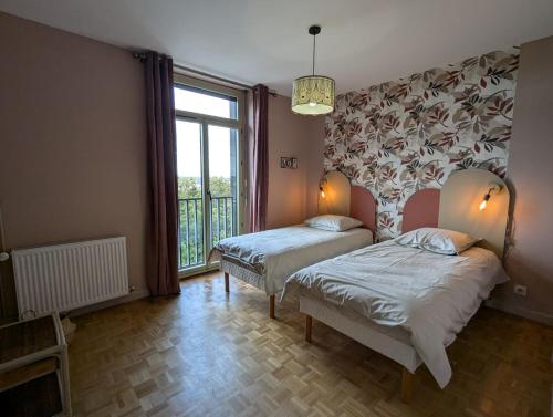 een slaapkamer met twee bedden en een groot raam bij Sylonie in Châteauroux