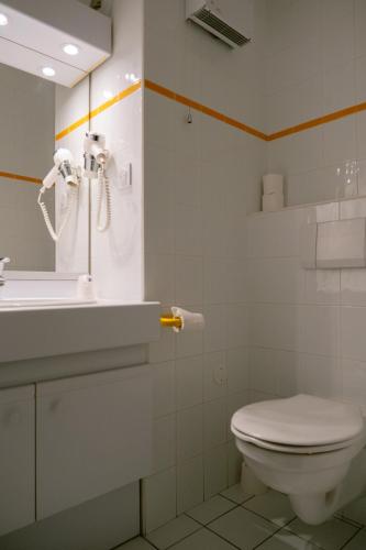 une salle de bain blanche avec des toilettes et un lavabo dans l'établissement Club Vacances Bleues Les Horizons du Lac (anciennement Serre-du-Villard), à Chorges