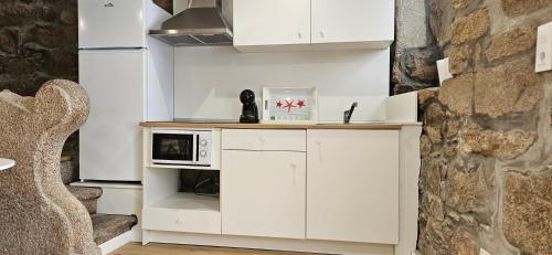 a kitchen with white cabinets and a microwave at Apartamentos Mirador de San Telmo in Tui