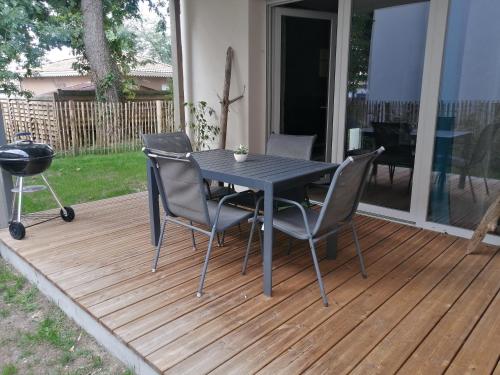 une table et des chaises noires sur une terrasse en bois dans l'établissement Appartement calme avec jardin dans résidence neuve, à Carcans