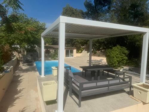 - un pavillon avec une table et des bancs à côté d'une piscine dans l'établissement Bergerie, à Marseille