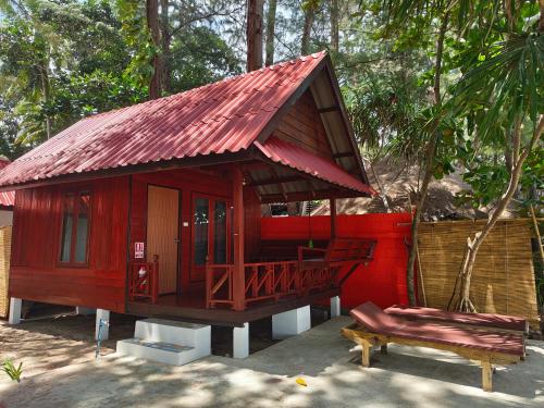 a small red house with a bench in front of it at Ziggy Stardust in Ko Phayam