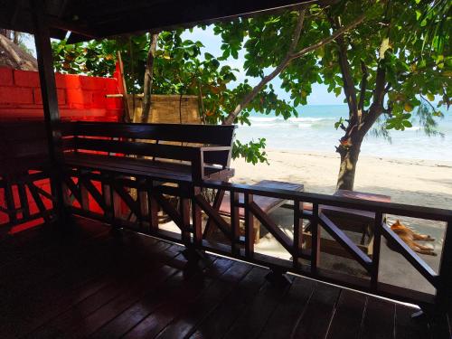 a bench on a beach with the ocean in the background at Ziggy Stardust in Ko Phayam