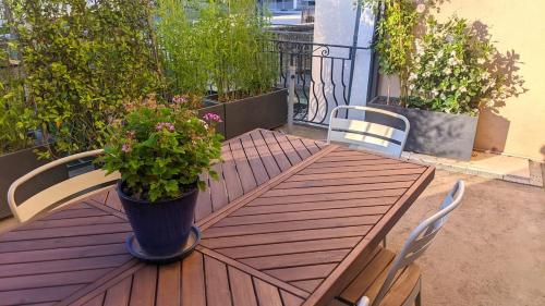 a wooden table with a potted plant on a balcony at Chambre Voltaire ou Chambre Beckett, terrasse en bord de Sorgue in Le Thor