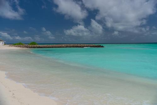 a beach with a small island in the water at Chao Guest House in Maafushi