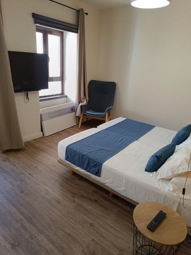 a bedroom with a bed and a tv and a chair at Apartamentos AL-QAZERES LUXURY La Concepción in Cáceres
