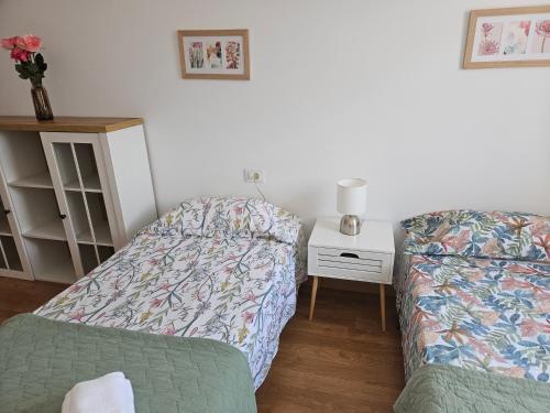 a room with two beds and a table with a lamp at Apartamentos Mirador de San Telmo in Tui