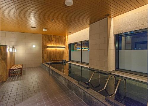 a swimming pool with a bench in a building at JR Inn Asahikawa in Asahikawa