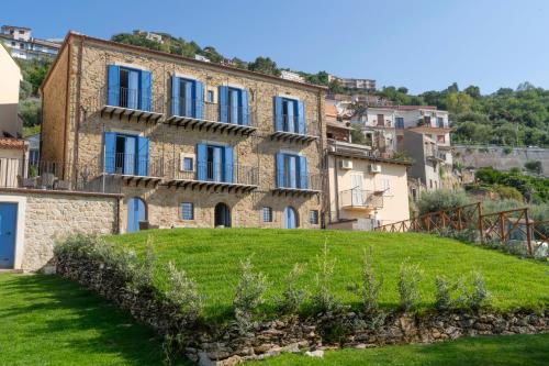 an old stone building on a hill with grass at Villa Vincenza Deluxe Rooms in Capo dʼOrlando