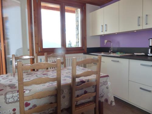 une cuisine avec une table et des chaises et une cuisine avec un évier dans l'établissement Appartement dans un chalet typique de montagne à La Rosière, à Montvalezan
