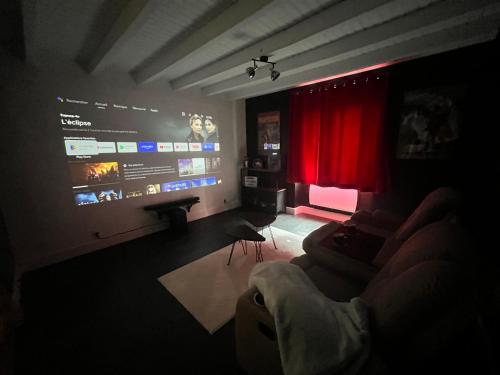 a living room with a large screen with a couch at L’Instant in Caupenne