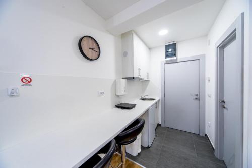 a white room with a counter and a clock on the wall at F Apartmani Kragujevac in Kragujevac