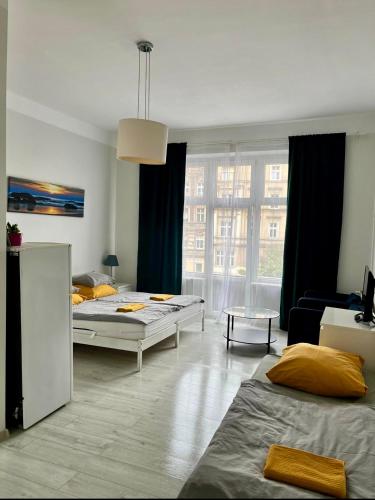 a bedroom with two beds and a living room at Colourful Rooms Wrocław in Wrocław