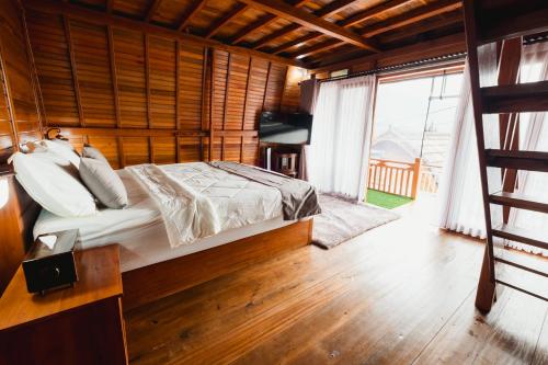 a bedroom with a bed and a large window at The Polumb Garden Bedugul in Tabanan