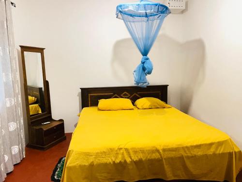 a bedroom with a yellow bed with a blue curtain at The Villa in Massalapitiya