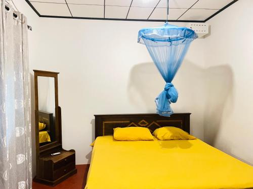 a bedroom with a yellow bed with a blue curtain at The Villa in Massalapitiya