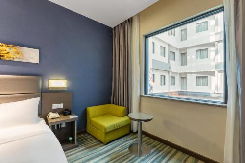 a hotel room with a bed and a chair and a window at Holiday Inn Express Shenyang North Station by IHG in Shenyang