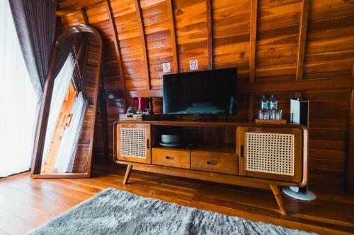 a living room with a tv on a wooden wall at The Polumb Garden Bedugul in Tabanan