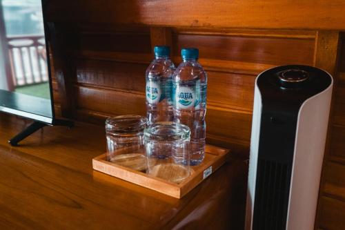 two bottles of water and glasses on a table at The Polumb Garden Bedugul in Tabanan