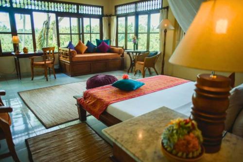 a bedroom with a bed and a couch and a table at Kavita 1 BR Grand Deluxe Valley View ZN236 in Ubud