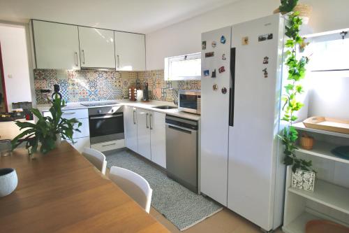 a kitchen with a table and a white refrigerator at Desertas Beach and Sport in Costa Nova