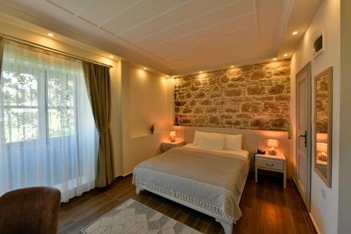 a bedroom with a bed and a brick wall at Cunda Ömer Ağa Konağı in Cunda