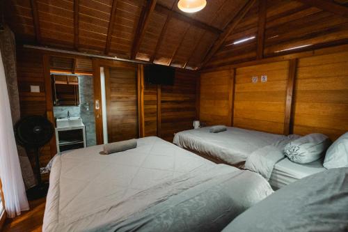 two beds in a room with wooden walls at The Polumb Garden Bedugul in Tabanan