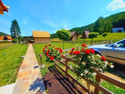 a car parked next to a fence with red flowers at Drveni raj Lopatnice in Lopatnica
