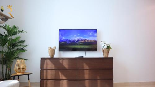 a living room with a tv on top of a dresser at Elegant 2BR Golf View Oasis in Yas Island - Maids Room, Pool & Near Yas Mall in Yas Island