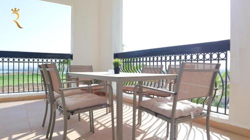 a table and chairs with a table and a balcony at Elegant 2BR Golf View Oasis in Yas Island - Maids Room, Pool & Near Yas Mall in Yas Island