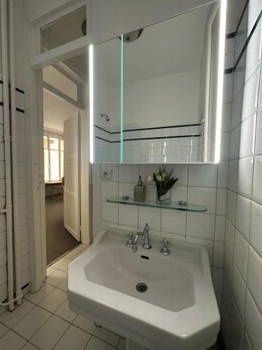 une salle de bain blanche avec un lavabo et un miroir dans l'établissement Luxury and cosy apartment in Paris, 16è Arrondissement, à Paris