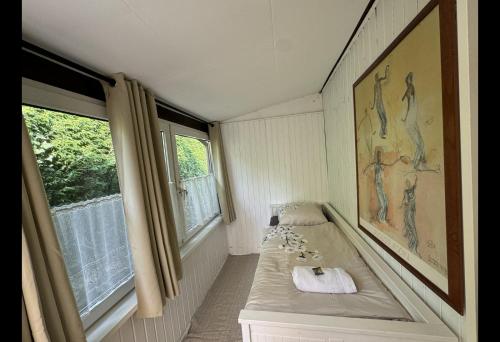 a small room with a bed and two windows at ART House /15 Min. Düsseldorf Messe,Airport & City in Meerbusch
